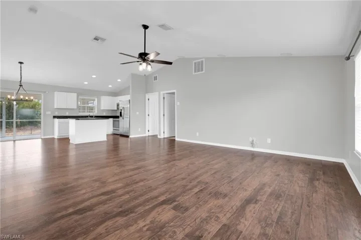 Unfurnished living room featuring suspended lighting, a high ceiling, dark wood-style flooring, and a ceiling fan