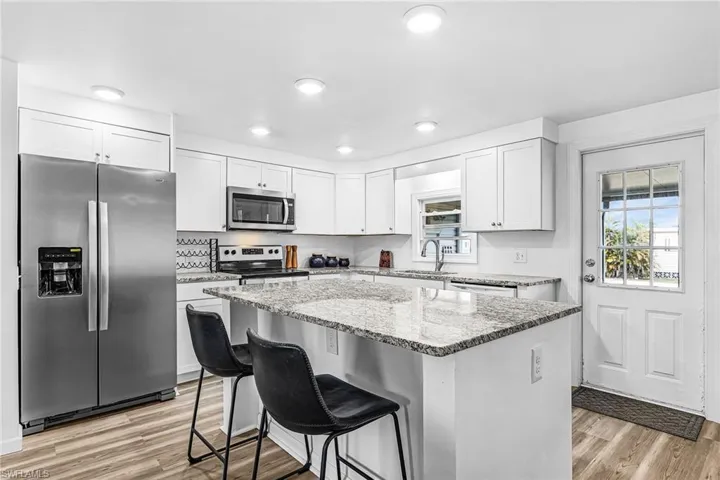 Dining area featuring wood-finish flooring, white walls, and a multi-bulb ceiling light fixture