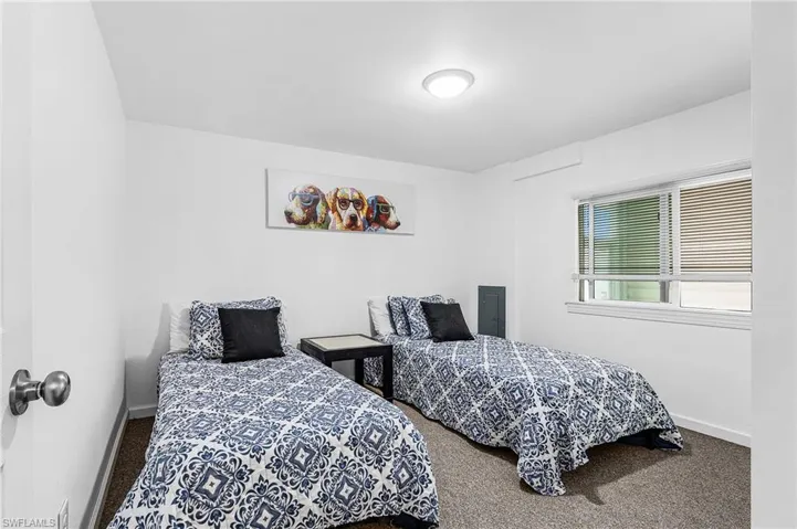 Carpeted room featuring white walls, a recessed window with blinds, and an overhead flush-mount light fixture