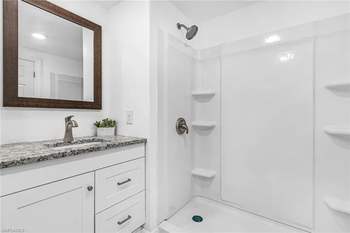 Bathroom featuring a single vanity with a granite countertop, undermount sink, and brushed nickel faucet