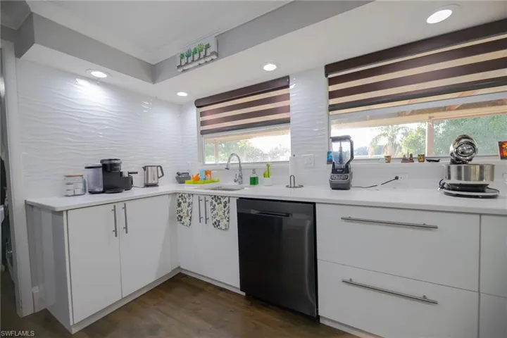 Kitchen featuring dishwasher, white cabinets, crown molding, sink, and dark hardwood / wood-style flooring