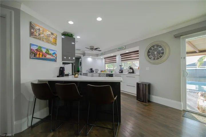 Bar featuring dark hardwood / wood-style flooring, white cabinetry, ceiling fan, and ornamental molding