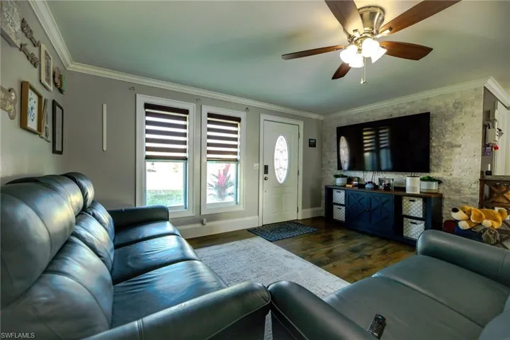 Living room featuring ceiling fan, dark hardwood / wood-style floors, and ornamental molding