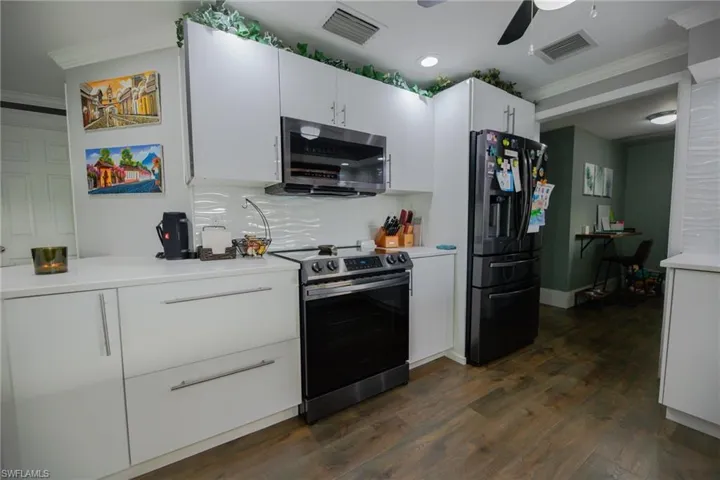 Kitchen featuring crown molding, white cabinets, stainless steel appliances, and dark hardwood / wood-style floors