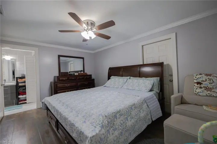 Bedroom with dark hardwood / wood-style flooring, ceiling fan, and crown molding