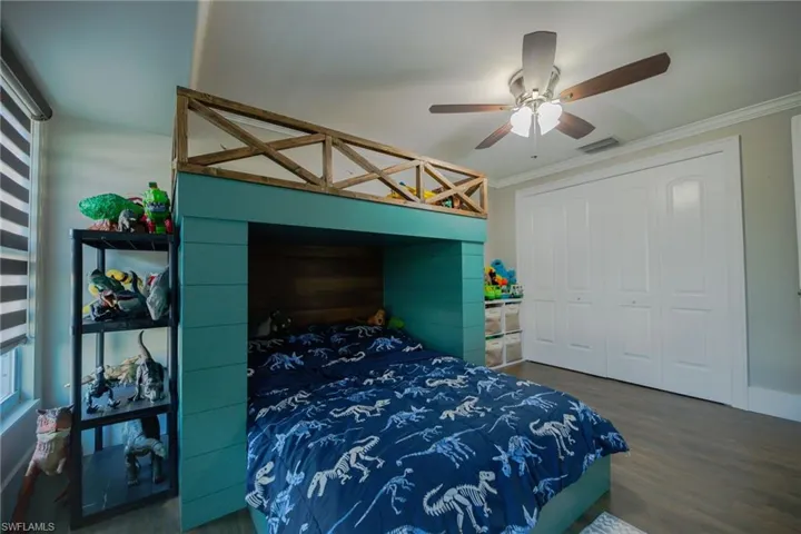 Bedroom with ceiling fan, a closet, dark hardwood / wood-style floors, and ornamental molding