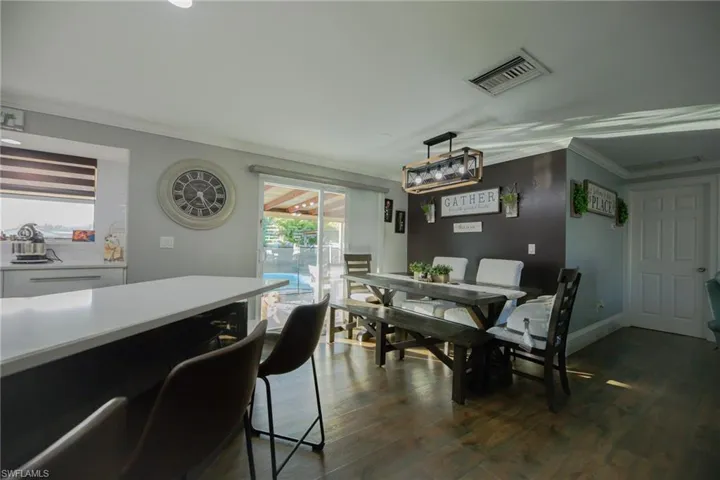 Dining space featuring dark hardwood / wood-style flooring, a healthy amount of sunlight, and ornamental molding