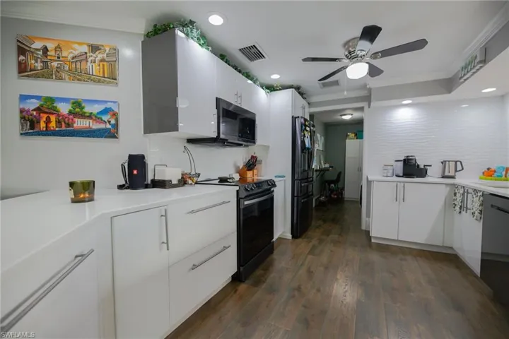 Kitchen featuring ornamental molding, ceiling fan, black appliances, dark hardwood / wood-style floors, and white cabinetry