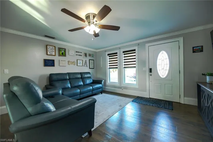 Living room featuring ceiling fan, dark hardwood / wood-style flooring, and ornamental molding