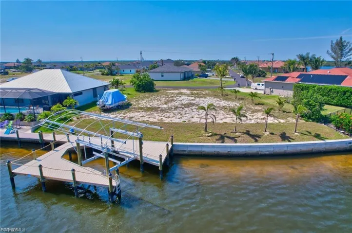 Dock with boat lift, a residential view, and a water view