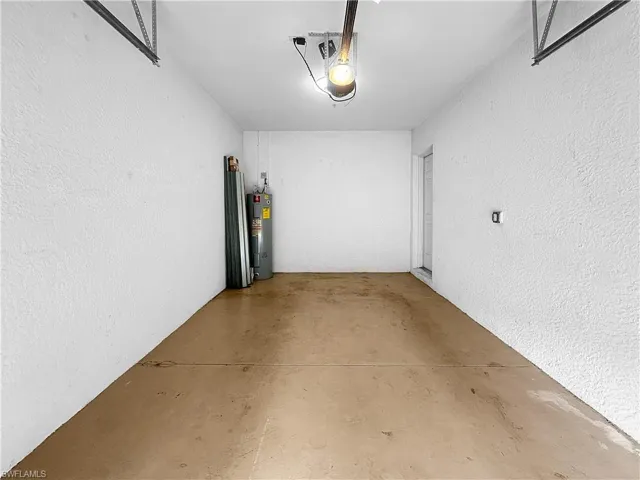 Garage featuring electric water heater, a textured wall, and a garage door opener