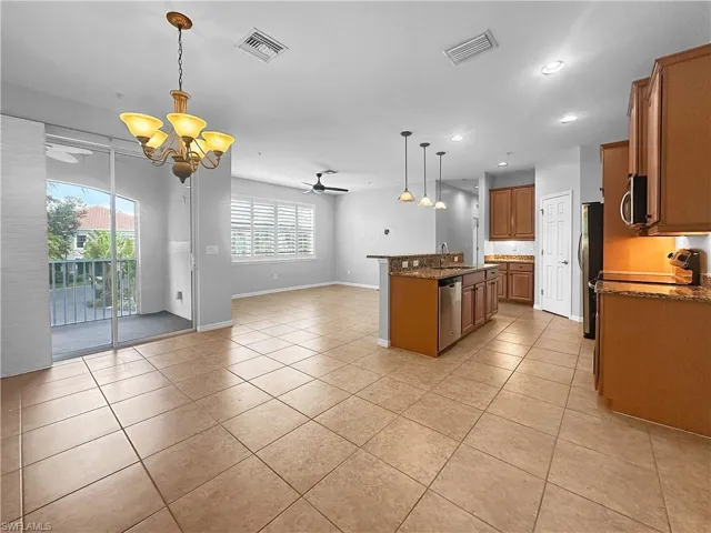 Kitchen with stainless steel appliances, a chandelier, open floor plan, light tile patterned floors, and recessed lighting