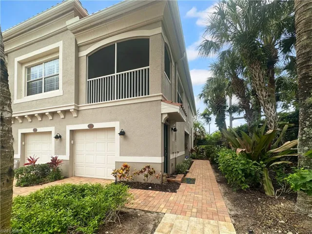 View of front of home featuring stucco siding, an attached garage, and a balcony