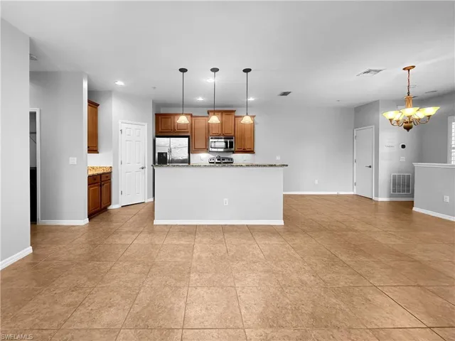 Kitchen with stainless steel appliances, a chandelier, recessed lighting, pendant lighting, and brown cabinetry