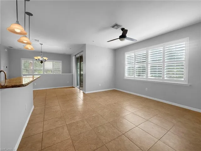 Tiled empty room with a chandelier, baseboards, and ceiling fan
