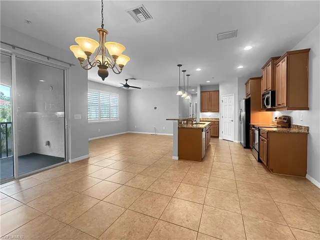 Kitchen with appliances with stainless steel finishes, a chandelier, a sink, open floor plan, and light tile patterned flooring