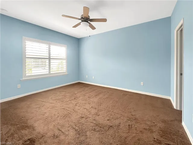 Carpeted spare room with a ceiling fan and baseboards