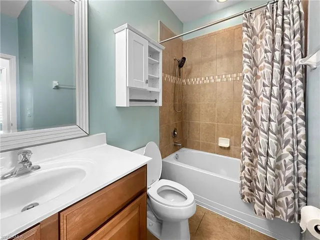 Full bath with vanity, shower / bath combo with shower curtain, tile patterned floors, and toilet