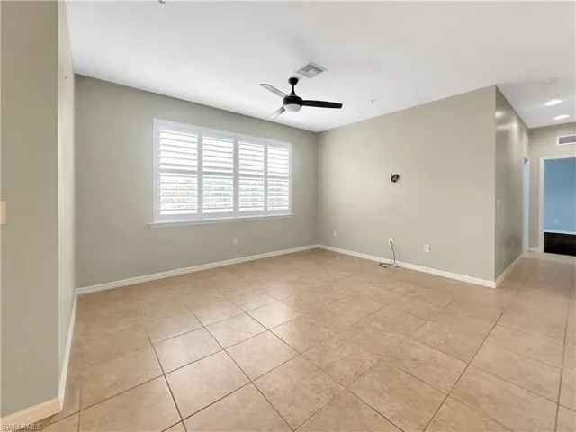 Spare room with light tile patterned floors, a ceiling fan, and baseboards