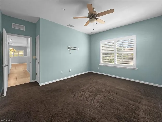 Carpeted spare room featuring plenty of natural light, a ceiling fan, and baseboards