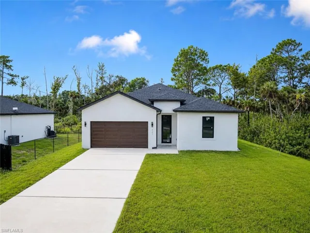 Contemporary exterior with white stucco finish, dark shingle roof, integrated garage, concrete driveway, and manicured lawn