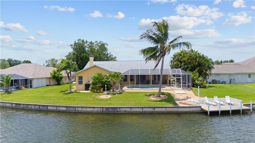 Canal-front property featuring a screened-in swimming pool and a private dock with four lounge chairs