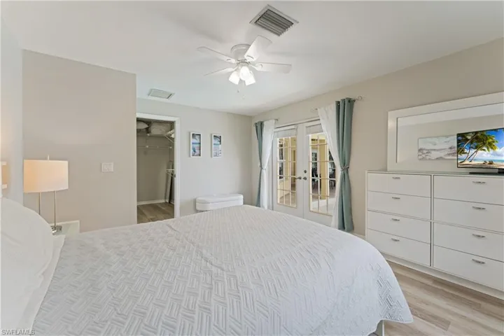 Bedroom featuring wood-finish flooring, a ceiling fan with integrated lighting, and a walk-in closet with built-in shelving