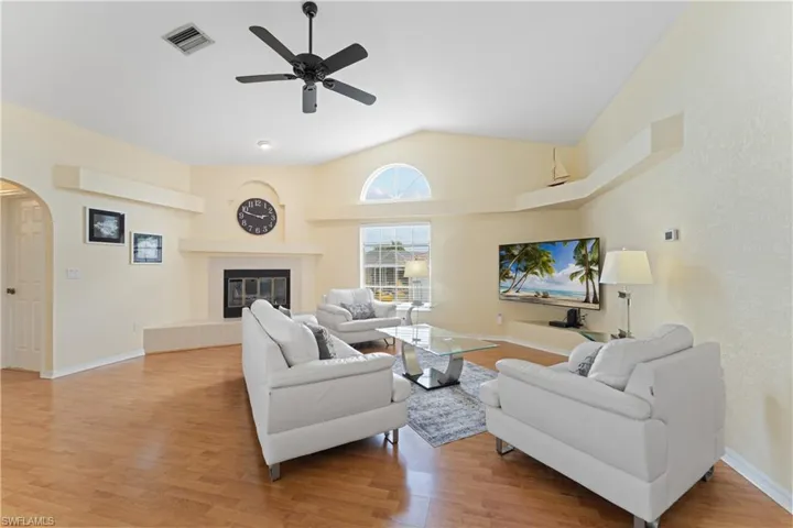 Spacious living area featuring wood-finish flooring, a vaulted ceiling, and an arched transom window