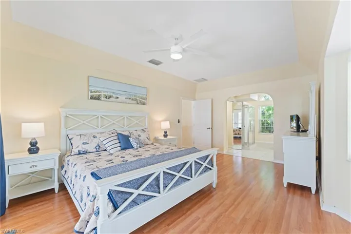 Spacious room featuring wood-finish flooring, a tray ceiling, and a ceiling fan