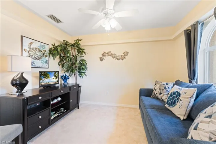Recessed ceiling with a white ceiling fan, light beige walls, and light-colored carpet flooring