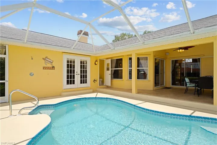 Screened swimming pool with a curved design, featuring a tile border and handrail access