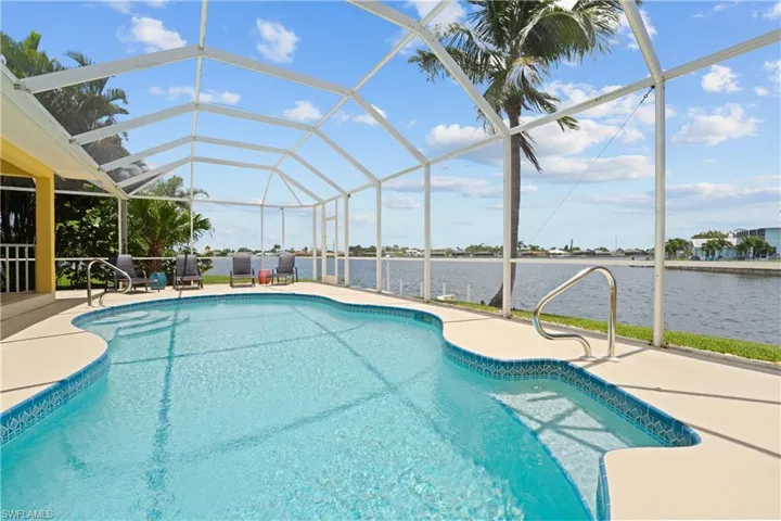 Freeform swimming pool with integrated steps, screened enclosure, and waterfront access