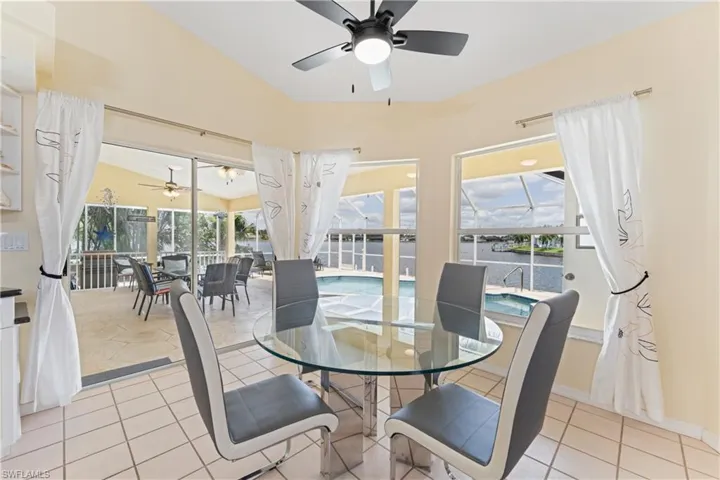 Dining area featuring light-toned tile flooring and a vaulted ceiling with a ceiling fan