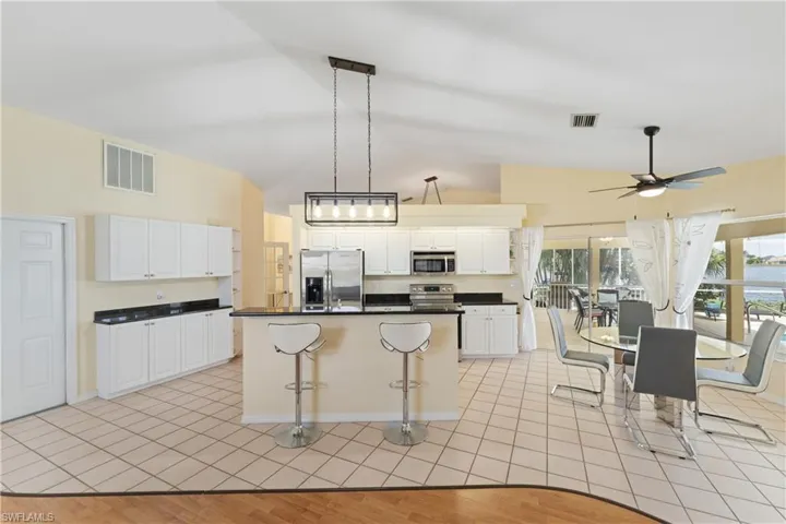 Kitchen featuring an island with bar seating, white cabinetry, dark countertops, and stainless steel appliances