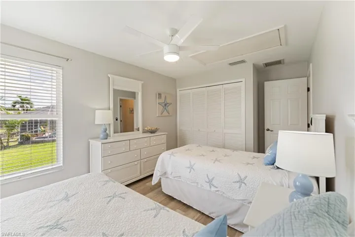 Bedroom with light gray walls, wood-finish flooring, a window featuring horizontal blinds, and a ceiling fan