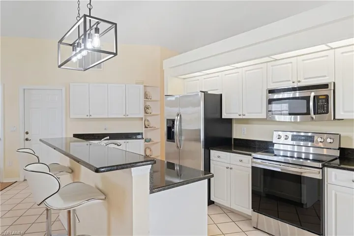 Kitchen featuring white cabinetry with dark countertops, stainless steel appliances, and tile flooring