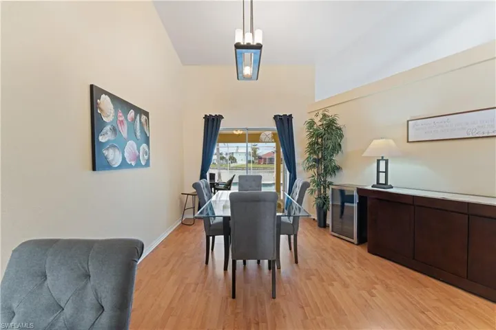 Vaulted ceiling dining area featuring wood-finish flooring, a contemporary chandelier, and direct access to an outdoor area