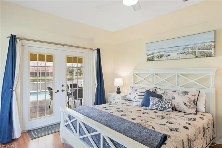 Bedroom featuring French doors, wood-finish flooring, and a ceiling fan