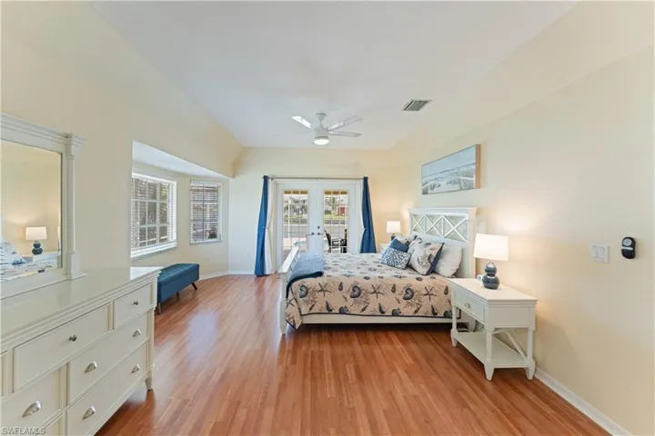 Spacious bedroom featuring wood-finish flooring, a tray ceiling, and a ceiling fan