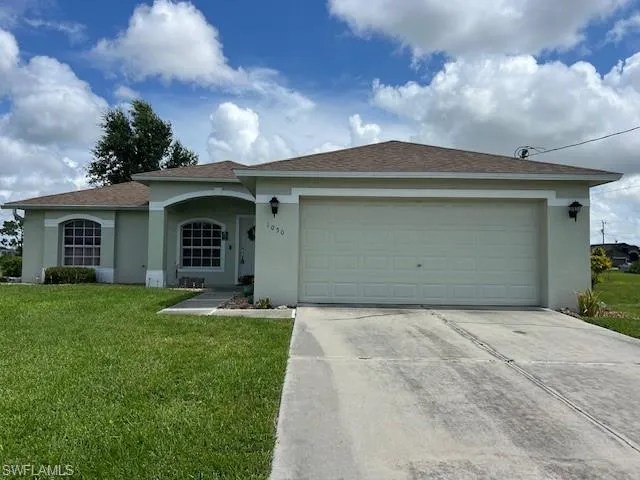 Ranch-style house featuring a garage and a front yard