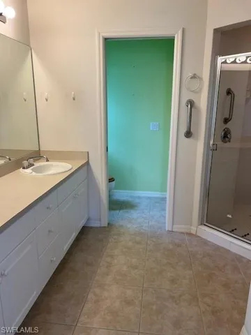 Bathroom featuring toilet, vanity, walk in shower, and tile patterned floors