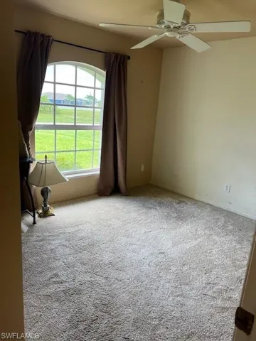 Carpeted empty room featuring ceiling fan