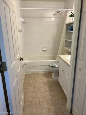 Full bathroom with tile patterned flooring, shower / tub combo with curtain, toilet, and vanity