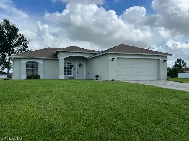 Ranch-style house with a garage and a front lawn