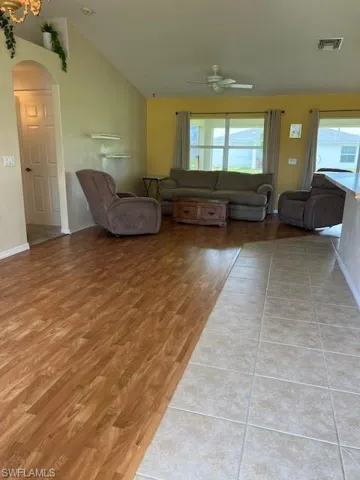 Living room featuring ceiling fan, light hardwood / wood-style flooring, and lofted ceiling