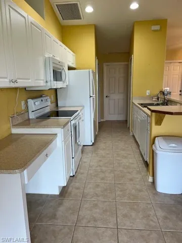 Kitchen featuring white cabinets, stove, and light tile patterned floors