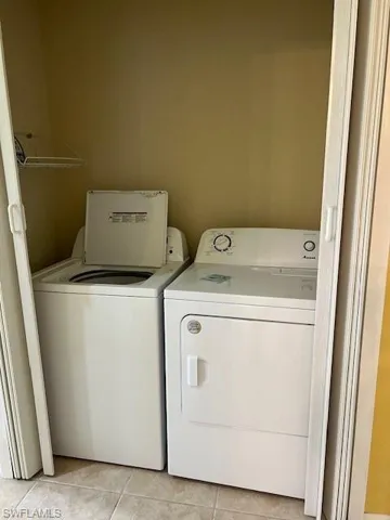 Laundry area featuring independent washer and dryer and light tile patterned floors