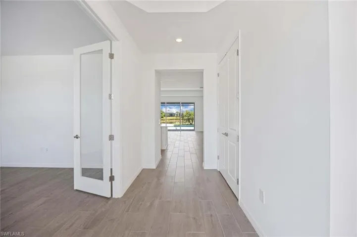 Hall featuring baseboards, french doors, recessed lighting, and wood finished floors