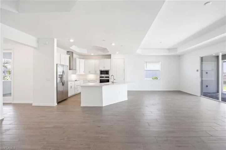 Kitchen with open floor plan, appliances with stainless steel finishes, wood finished floors, and a tray ceiling
