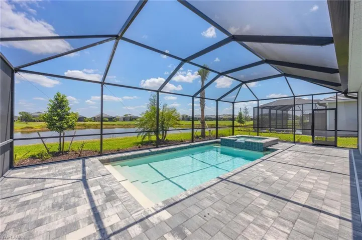 View of swimming pool featuring a patio, a water view, a lanai, and a pool with connected hot tub